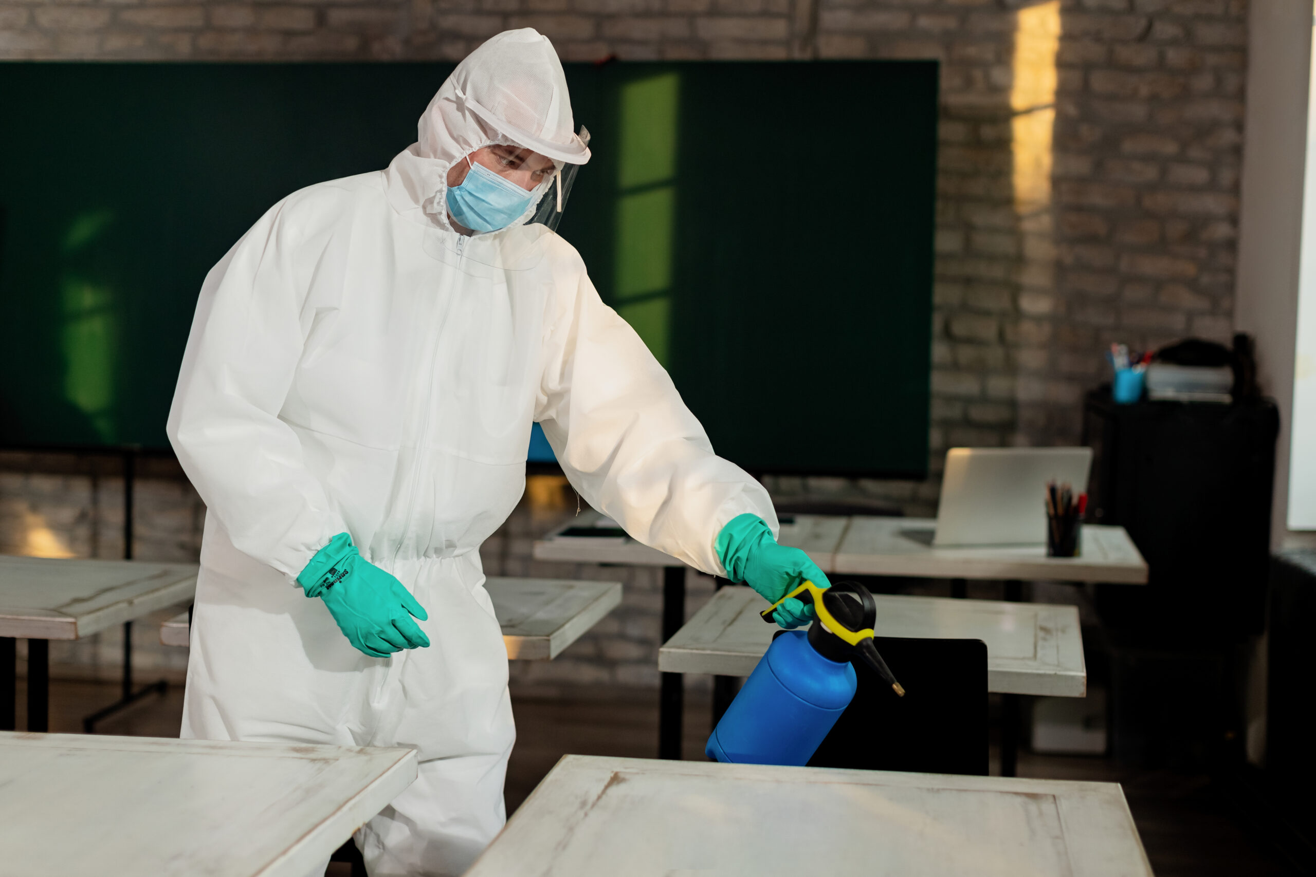 Man in hazmat suit disinfecting classroom due to coronavirus pan